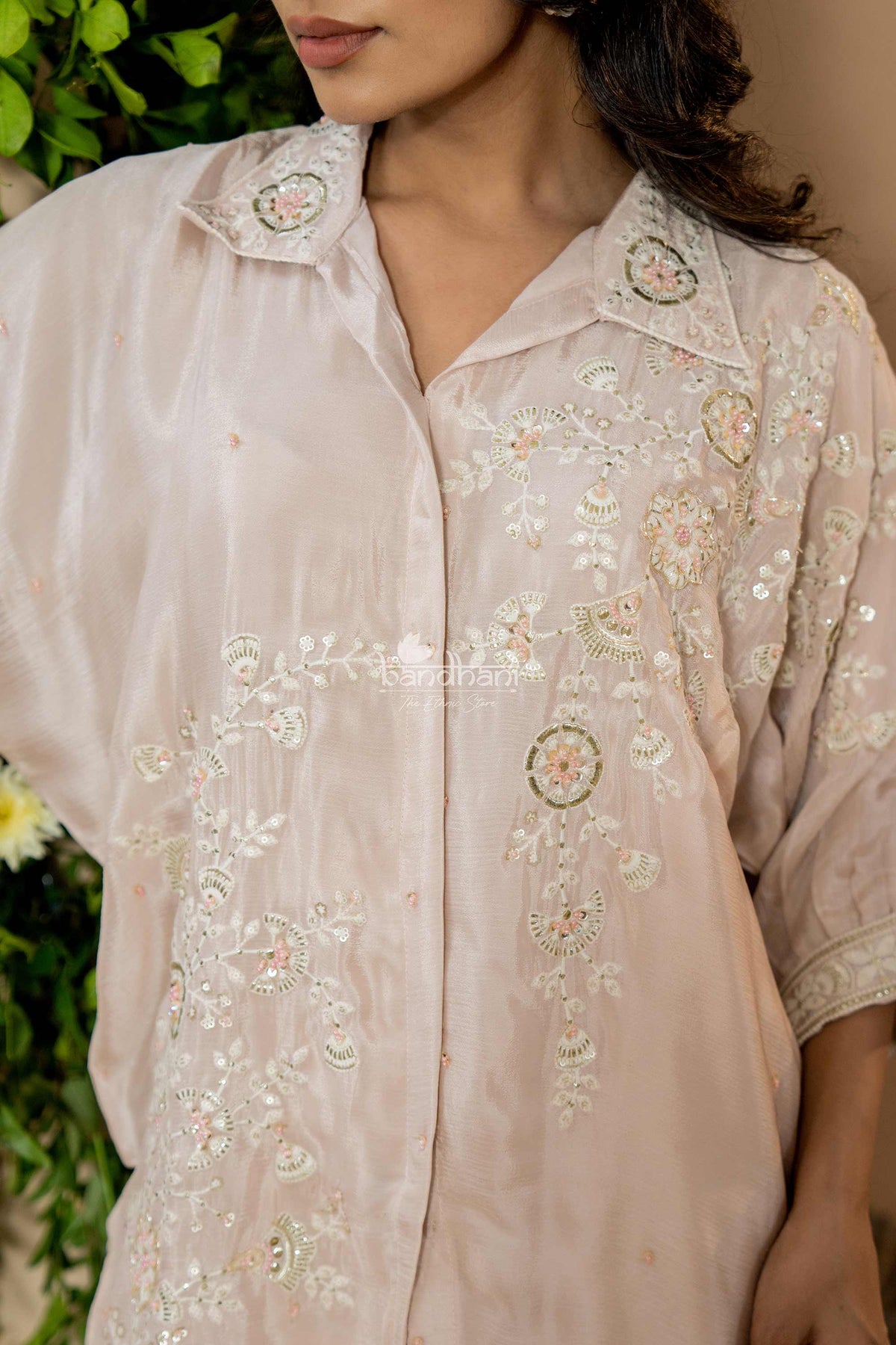 Light pink embroidered shirt worn by a person with a blurred background