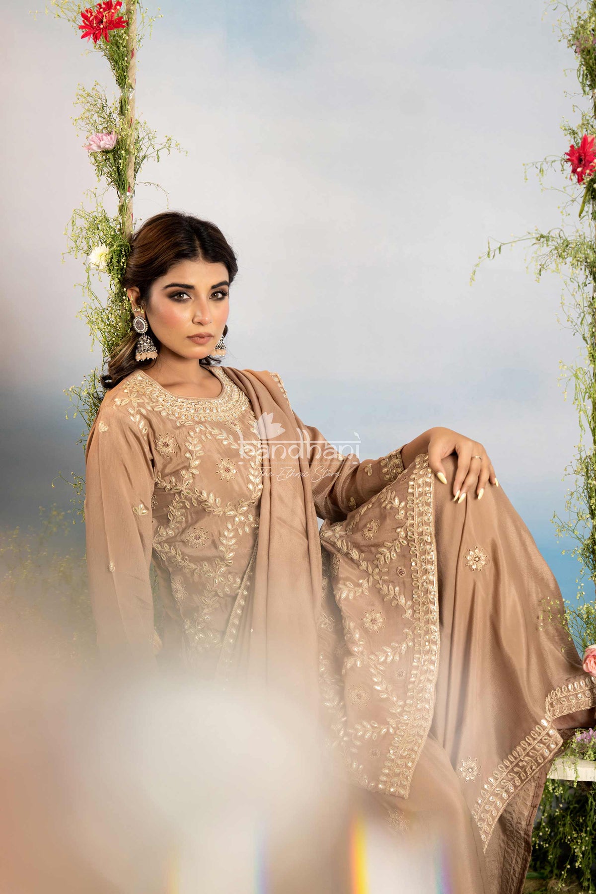 Woman in a beige embroidered traditional outfit with a floral background