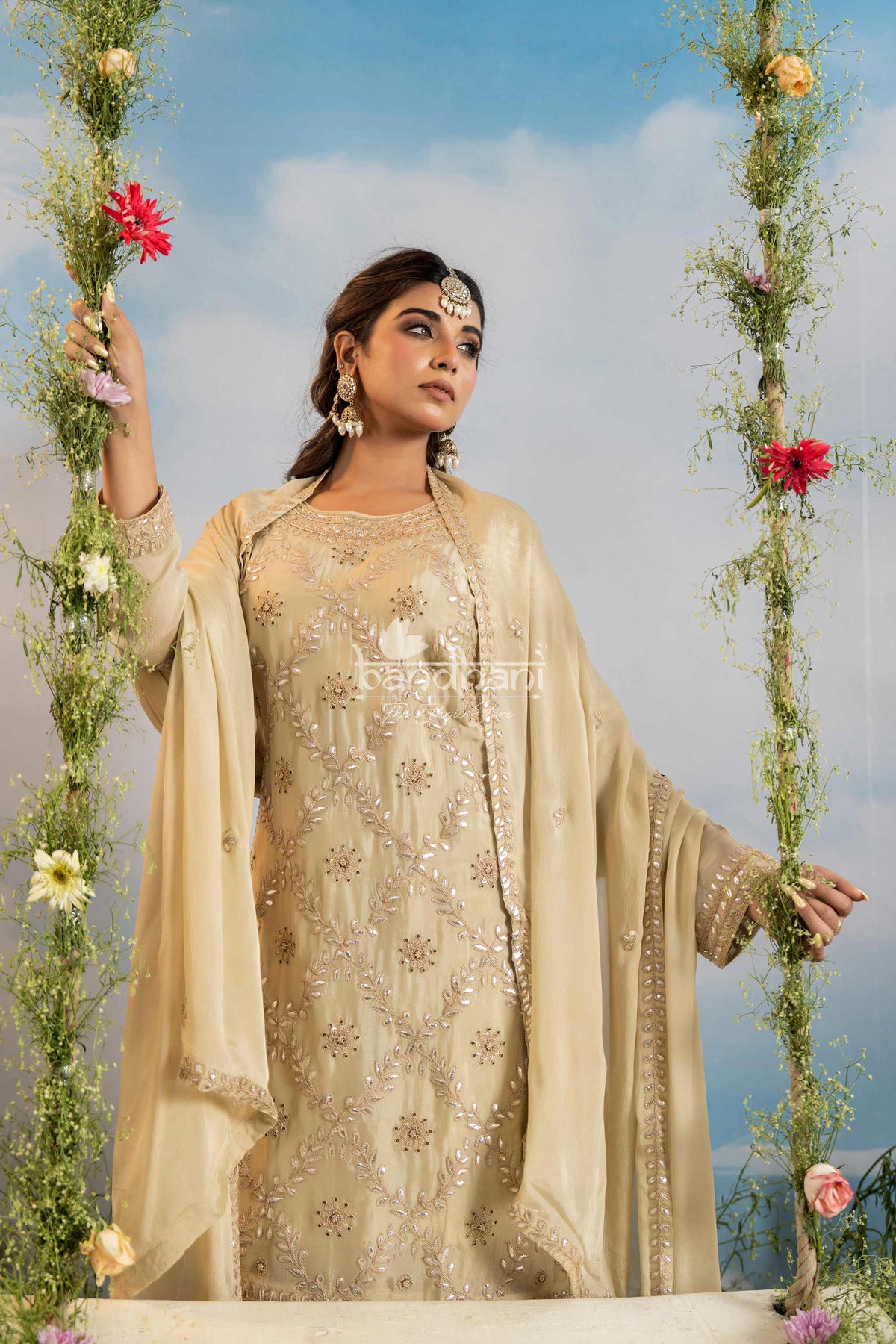 Woman in traditional beige embroidered outfit with floral decorations against a sky background