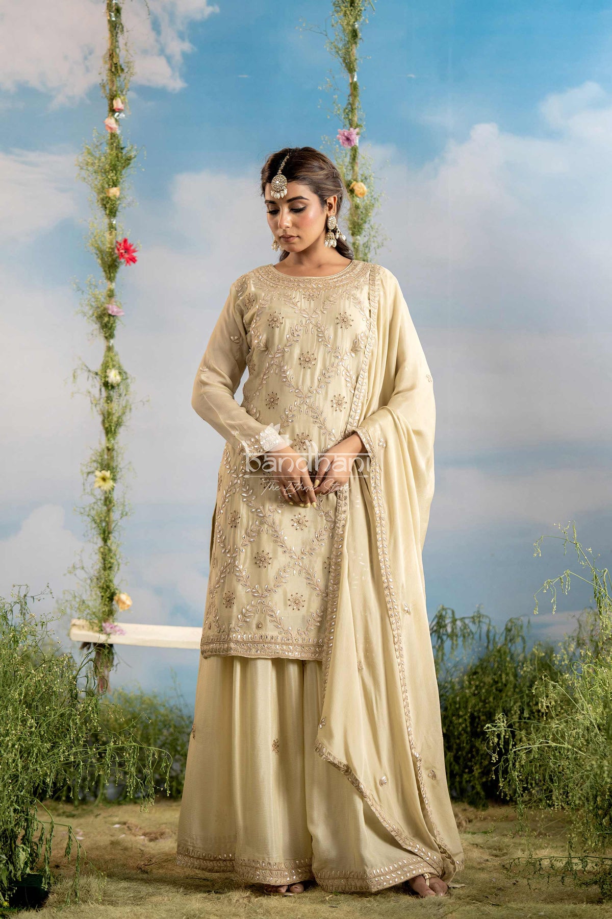 Woman in traditional beige outfit standing outdoors with a scenic background