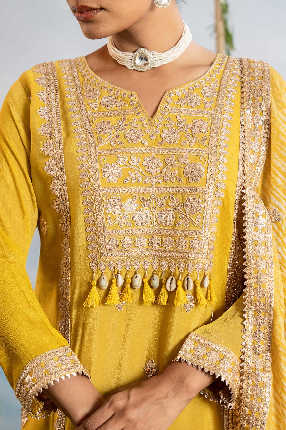 Yellow embroidered traditional outfit with intricate patterns and tassels.