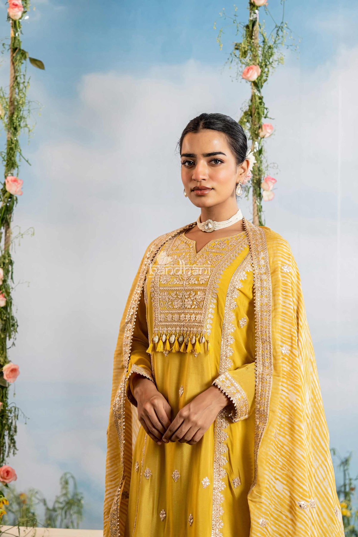 Woman in a yellow traditional outfit with floral decorations in the background