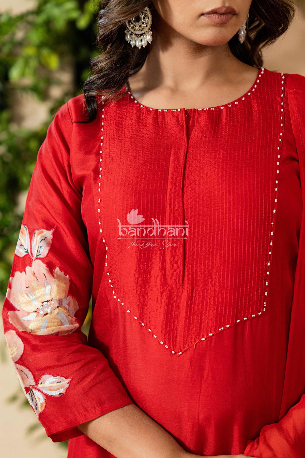 Red traditional outfit with floral embroidery and 'bandhani' branding.