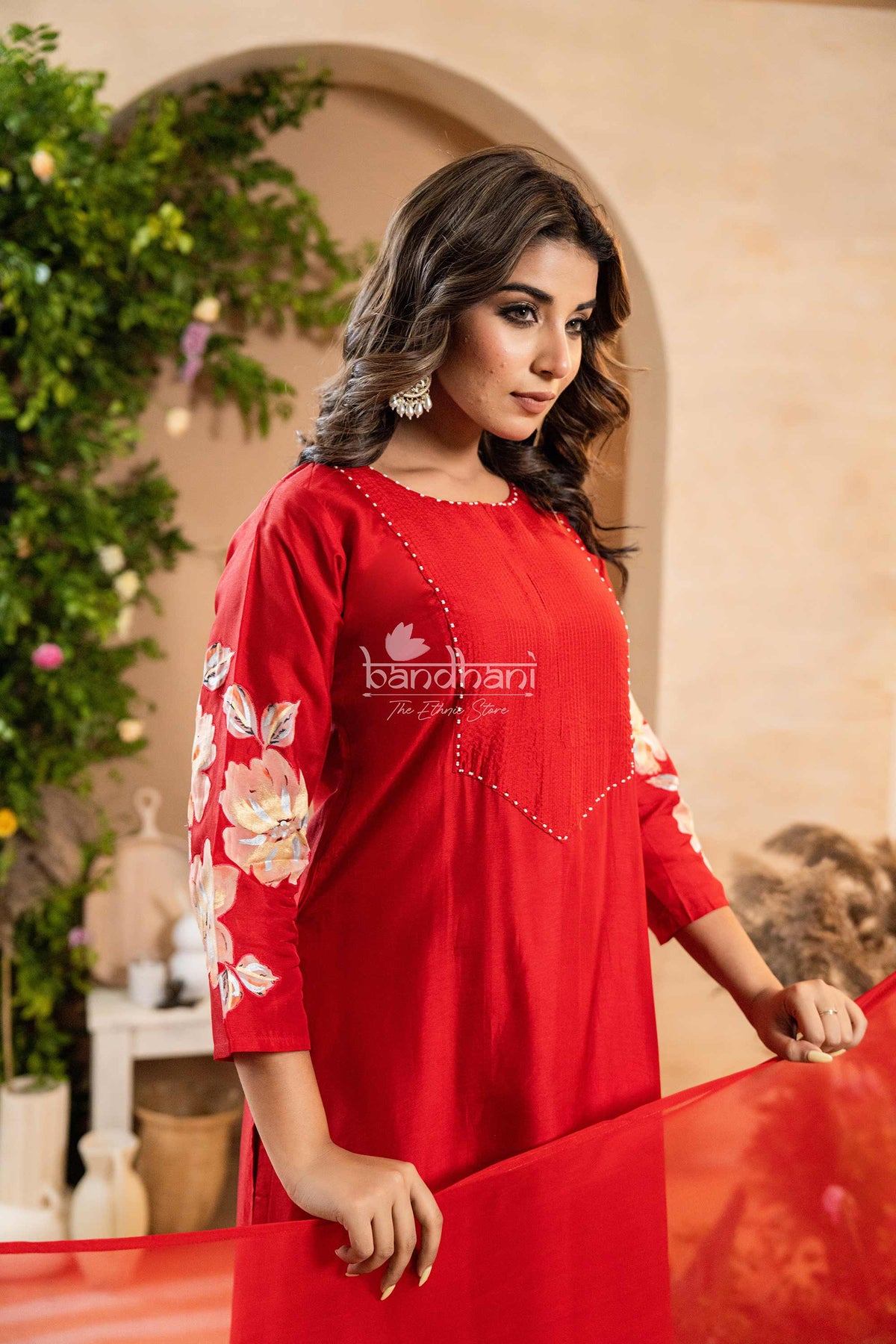 Woman wearing a red dress with floral sleeves in an outdoor setting