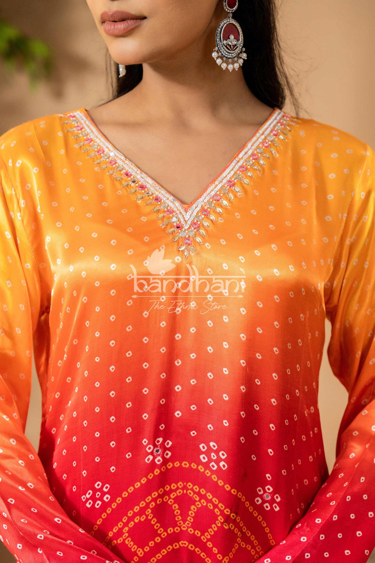 Woman wearing a colorful bandhani dress with intricate patterns.