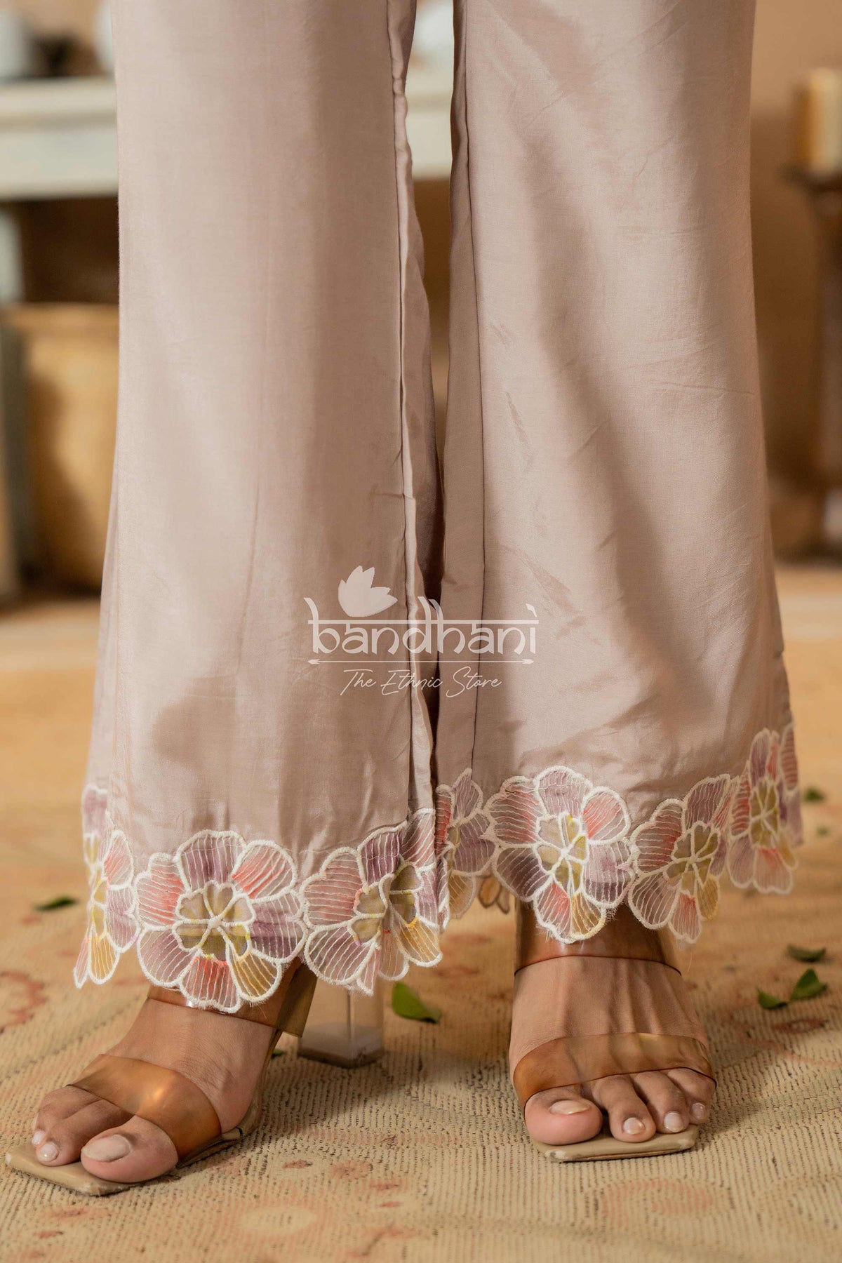 Beige pants with floral lace trim worn by a person, with 'bandhani' brand visible.
