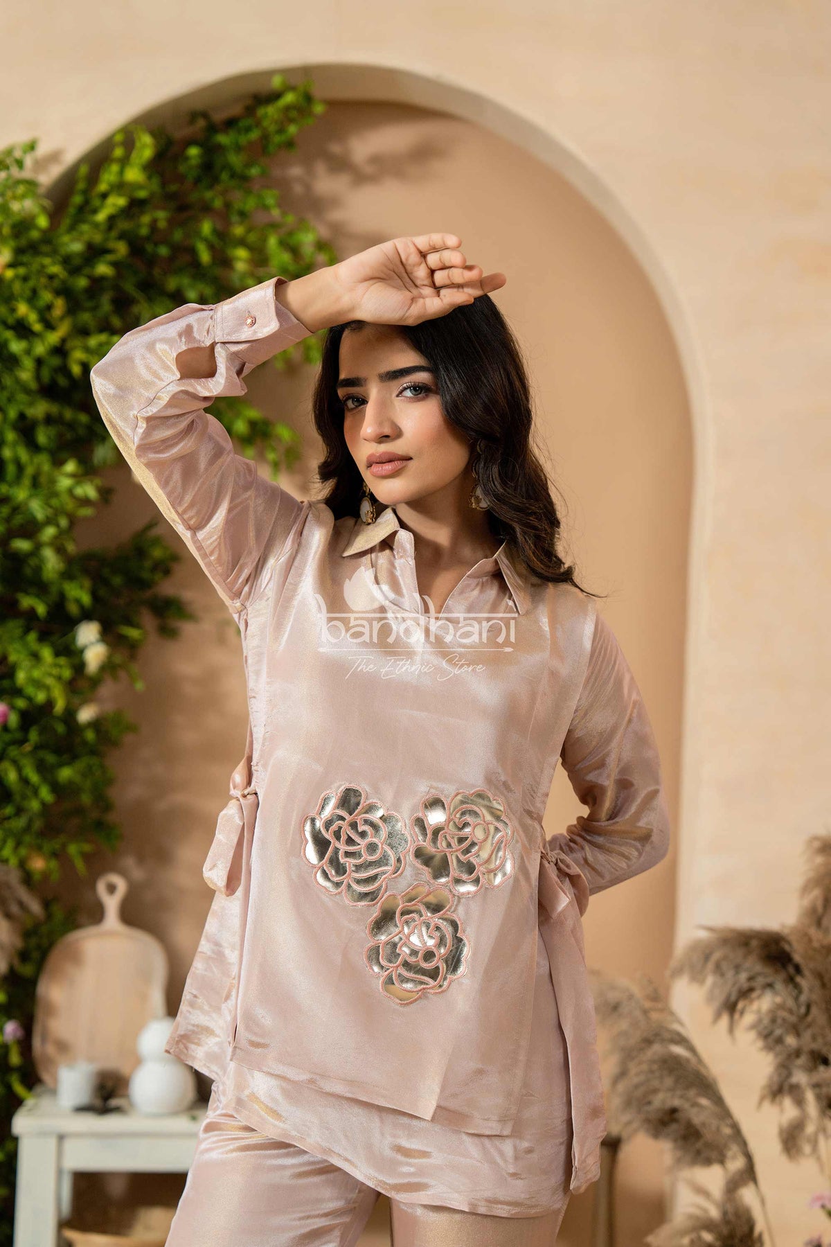 Woman wearing a light pink outfit with floral designs in an outdoor setting