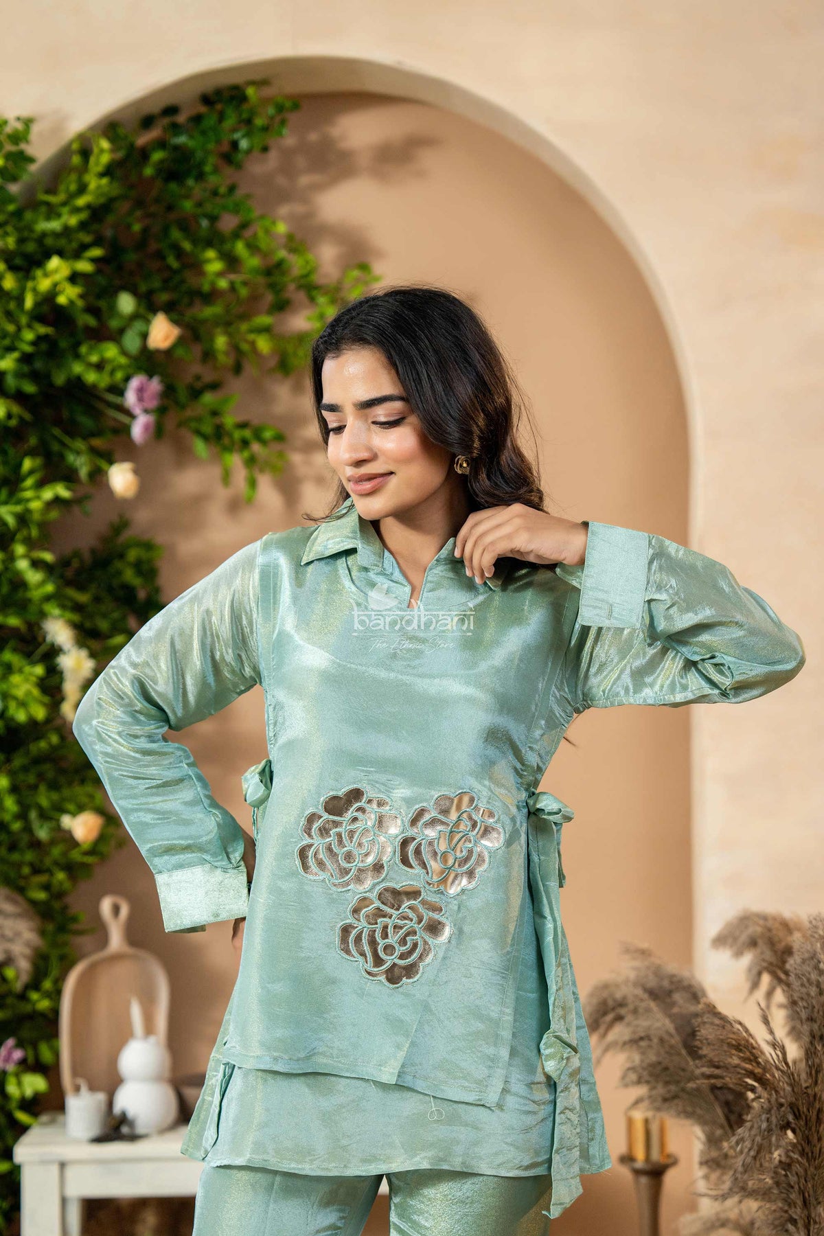 Woman wearing a light blue traditional outfit with floral patterns in an indoor setting.