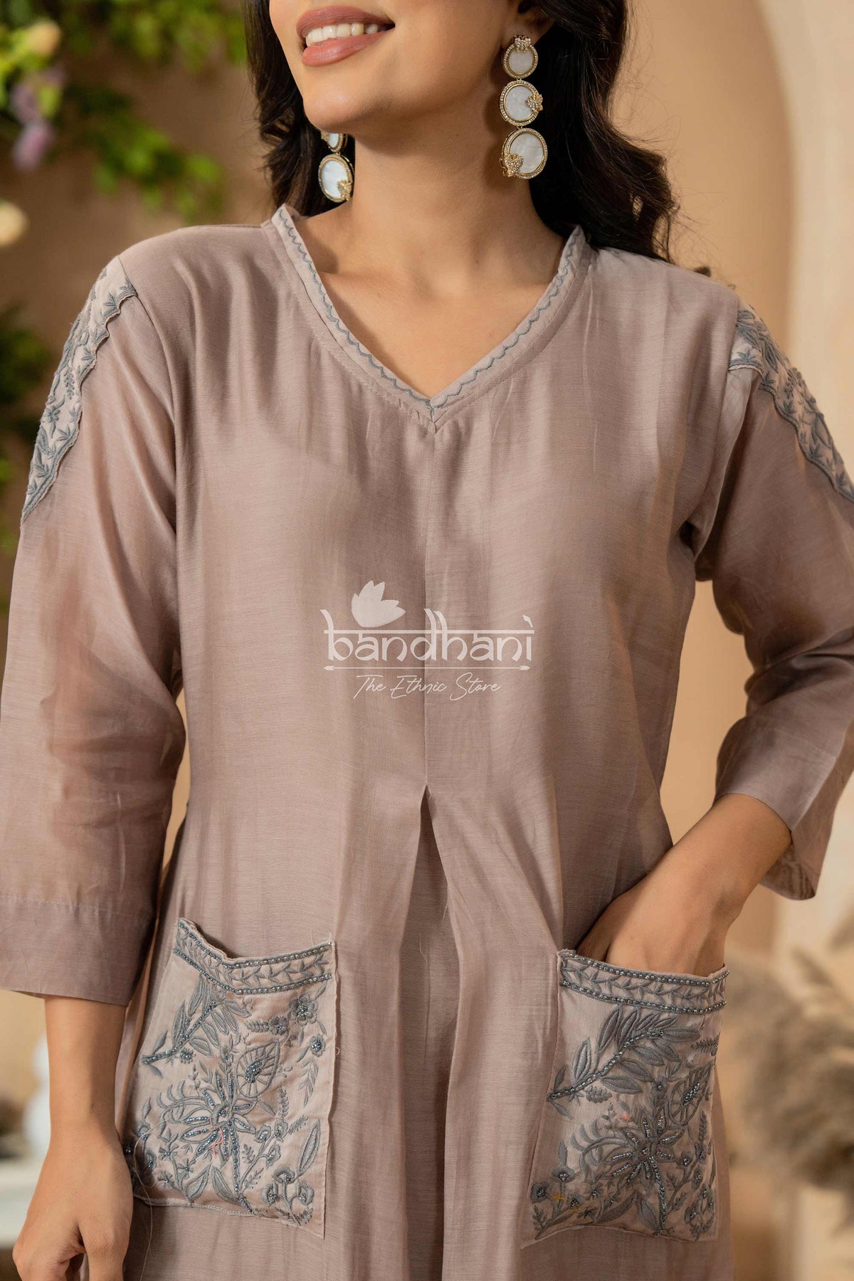 Woman wearing a brown dress with floral embroidery, brand 'bandhani' visible.