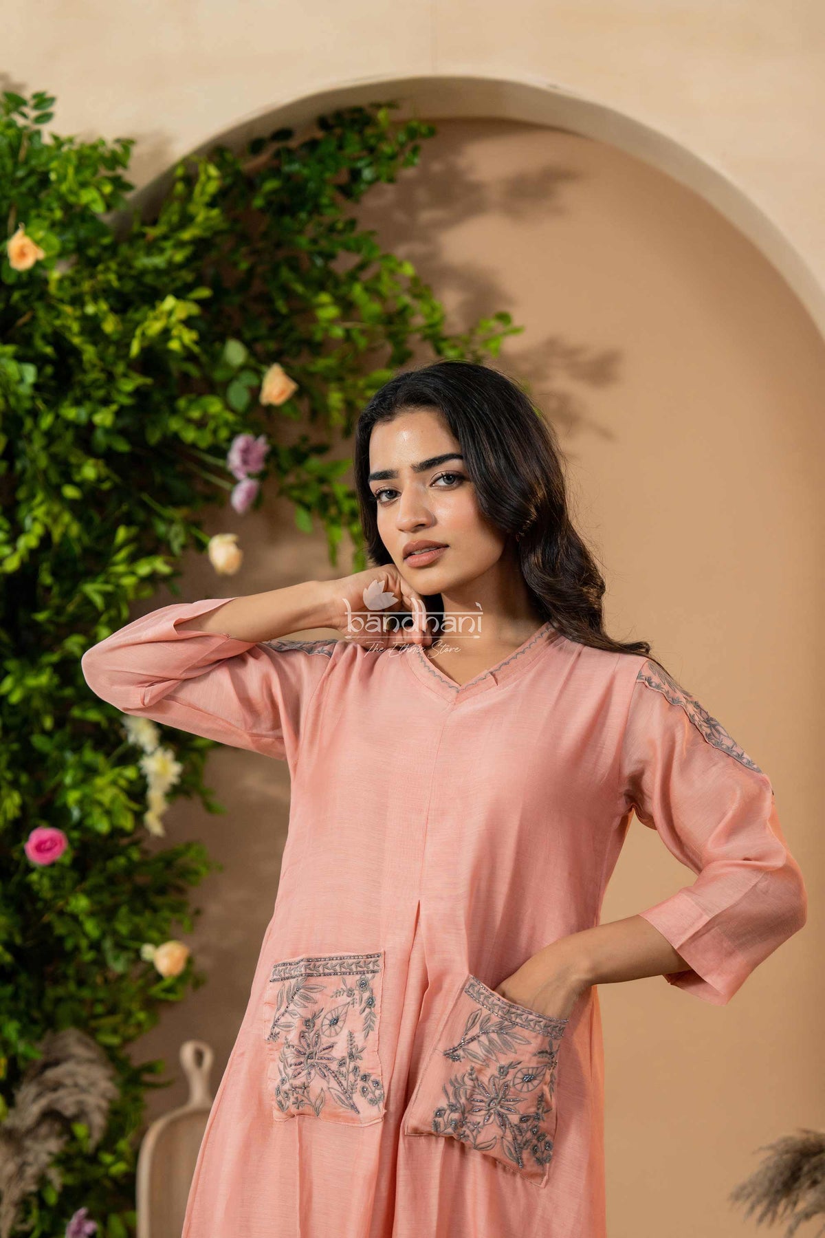 Woman wearing a pink dress with floral patterns in a decorated indoor setting