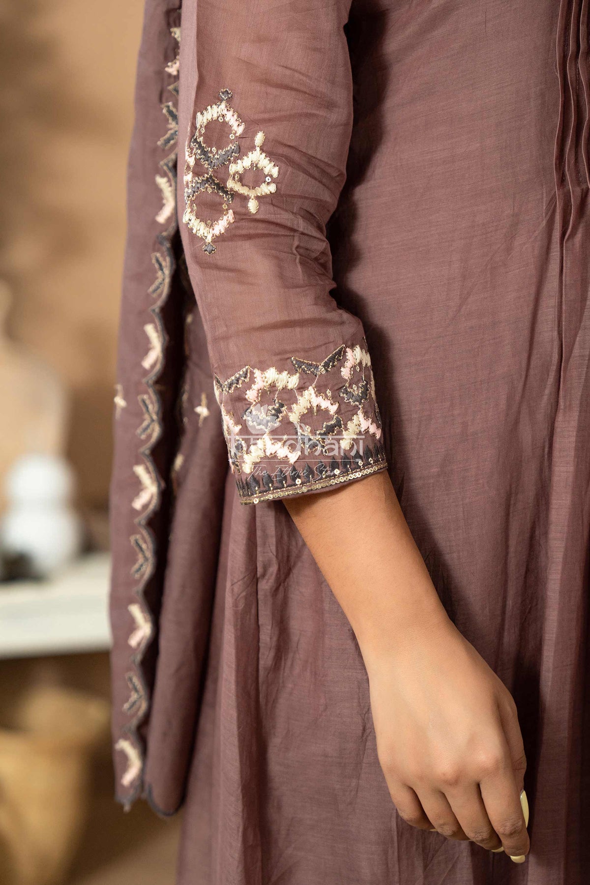 Brown traditional outfit with intricate white embroidery on a blurred background