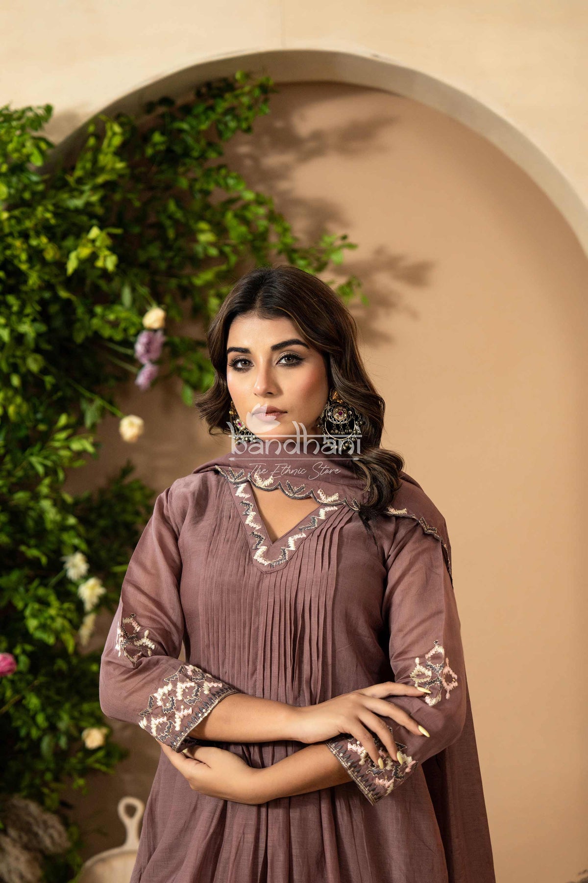Woman wearing a brown dress with intricate patterns in an outdoor setting