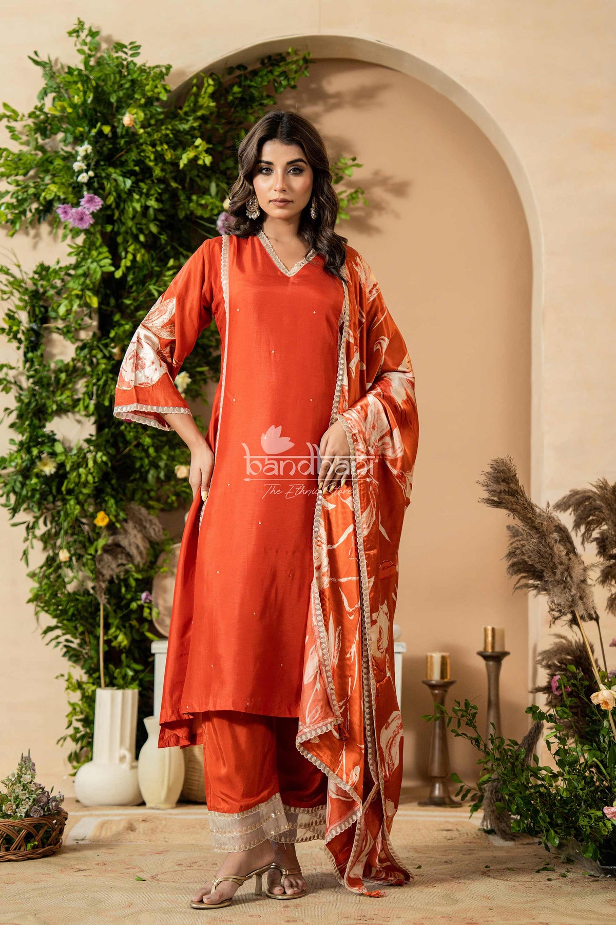 Woman in a red traditional outfit with a floral backdrop