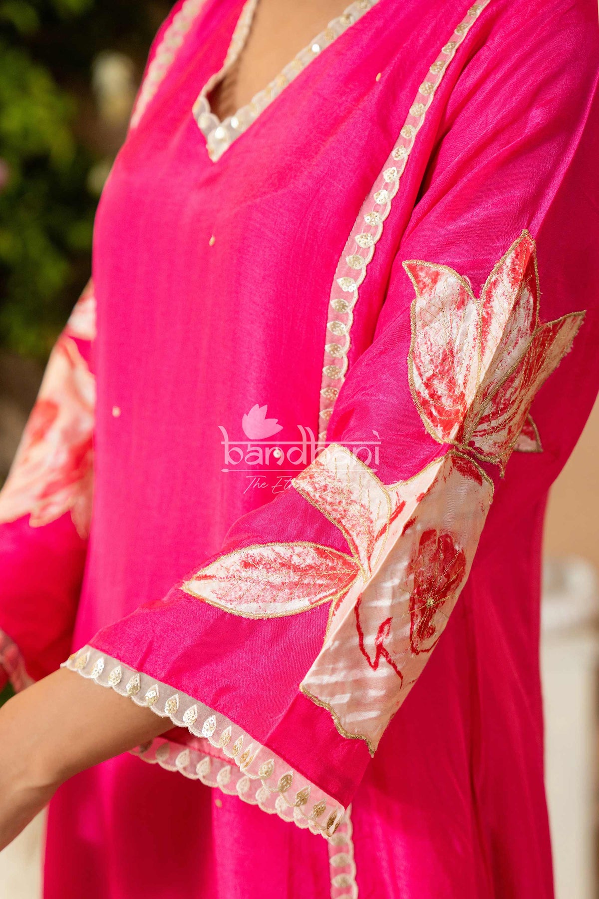 Close-up of a pink traditional outfit with floral embroidery and lace details.