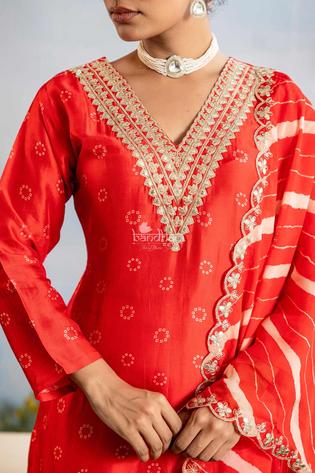 Red traditional outfit with intricate white embroidery on a neutral background