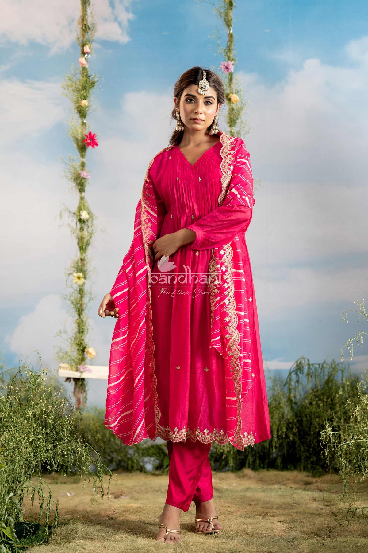 Woman in a bright pink traditional outfit standing outdoors with a scenic background