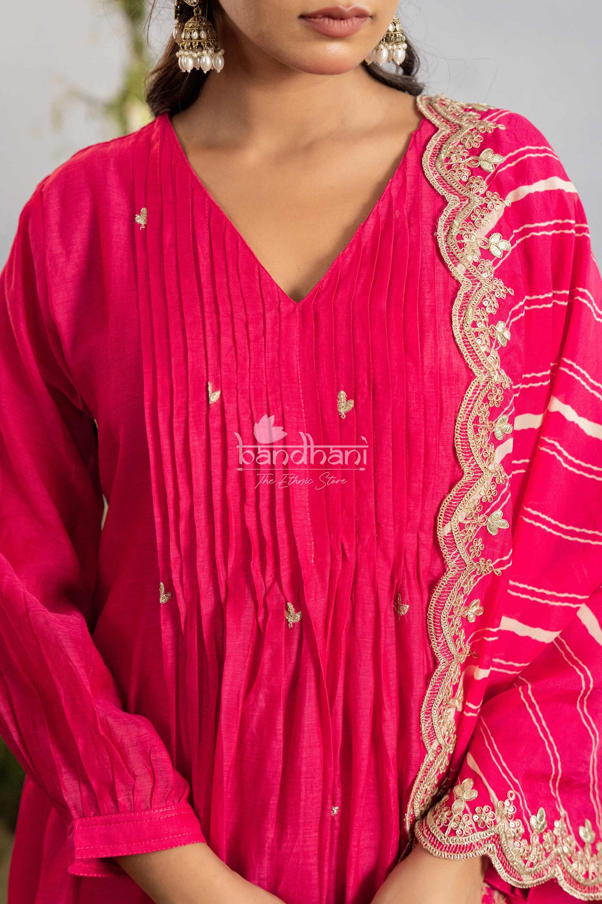 Close-up of a pink traditional outfit with intricate white embroidery on a neutral background