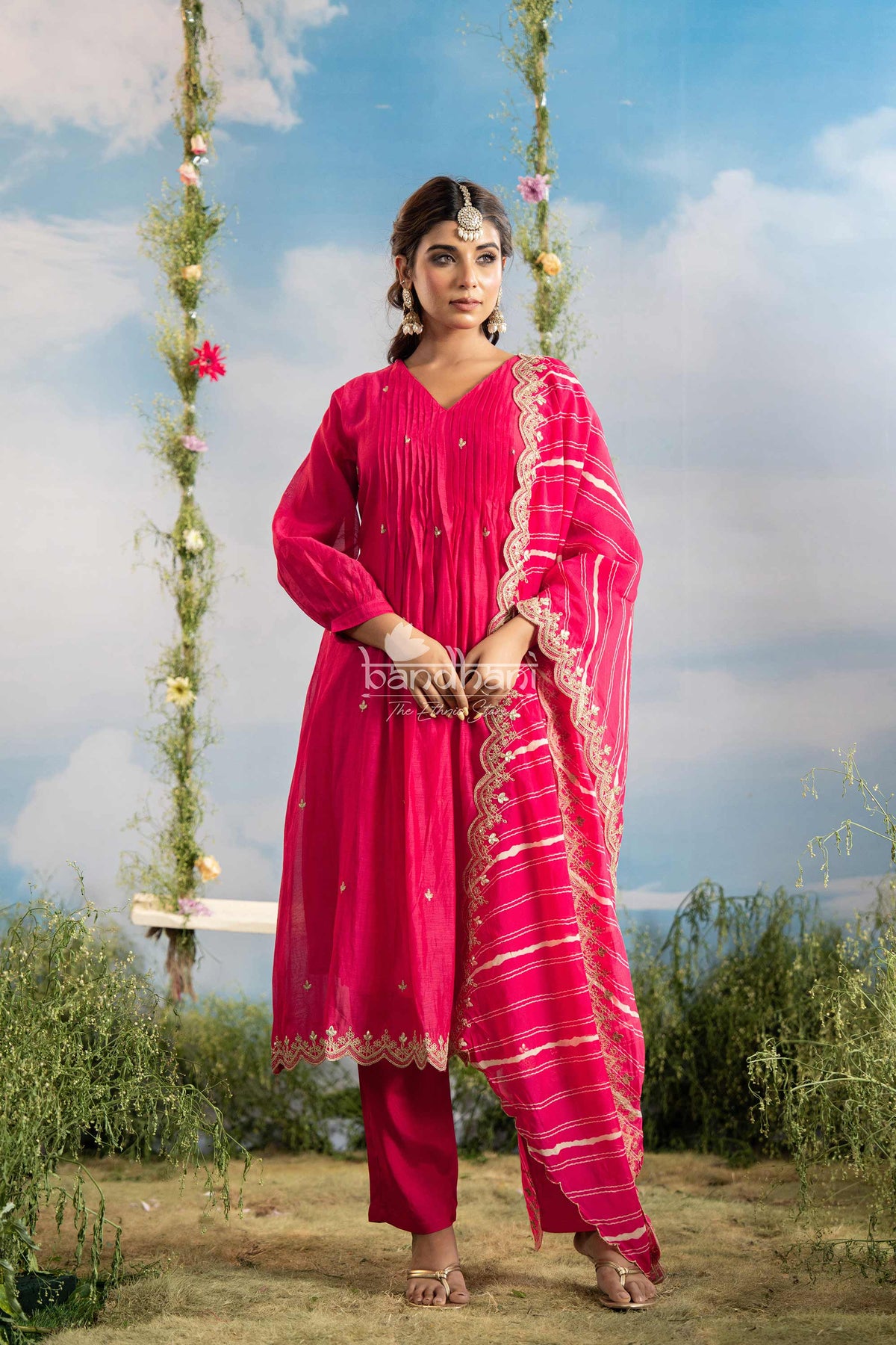 Woman in a pink traditional outfit standing outdoors with a scenic background