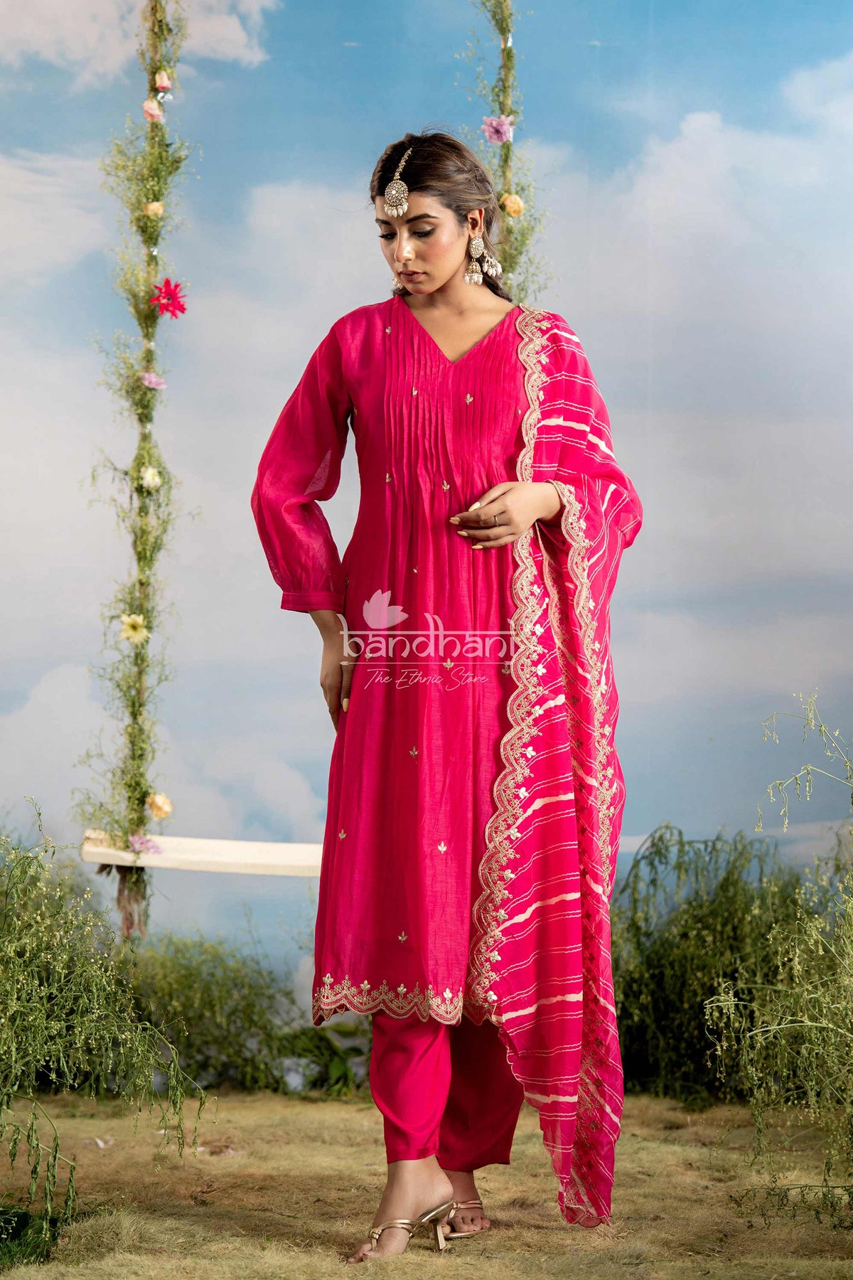 Woman in a bright pink traditional outfit with floral decorations in the background