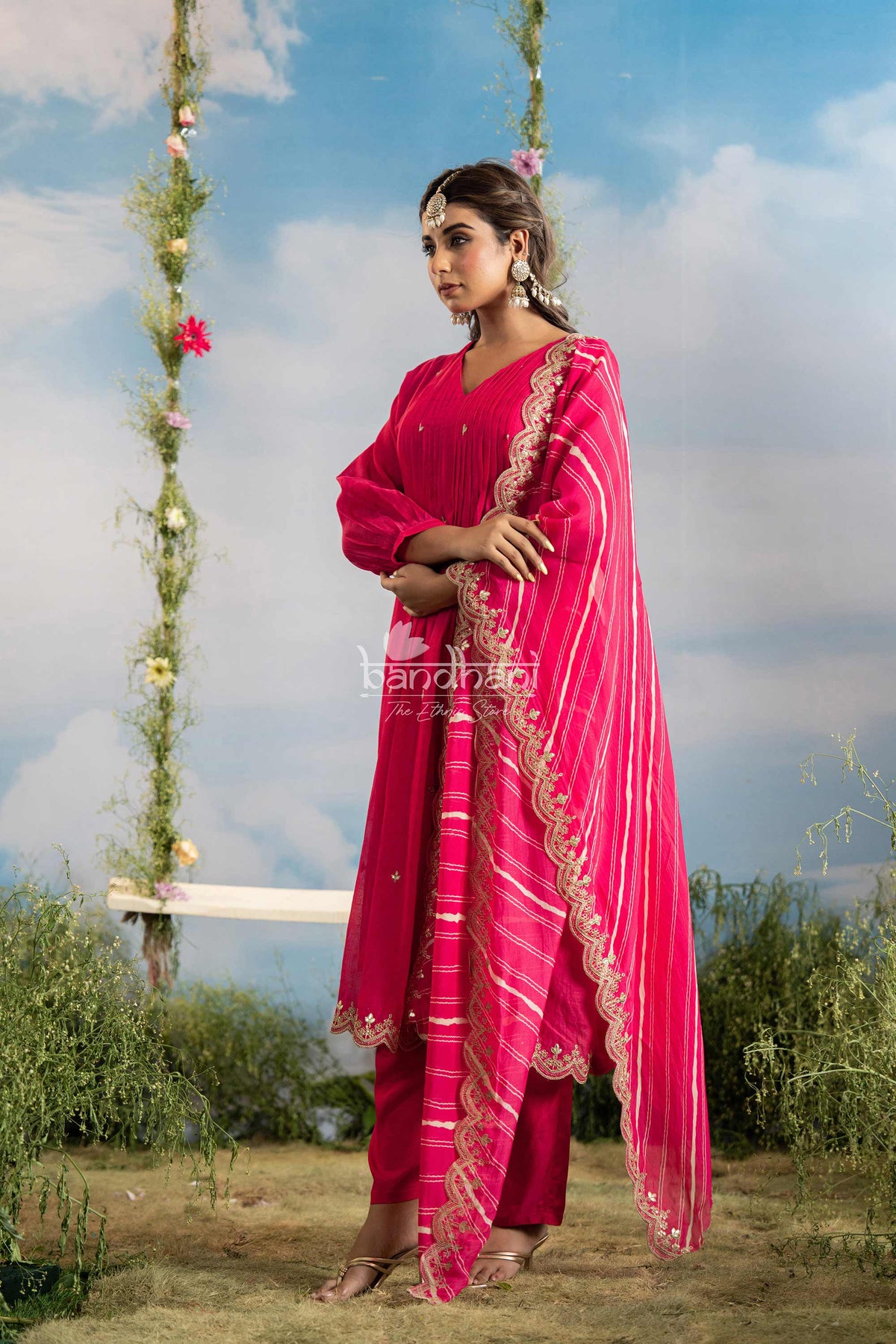 Woman in a pink traditional outfit standing outdoors with a scenic background