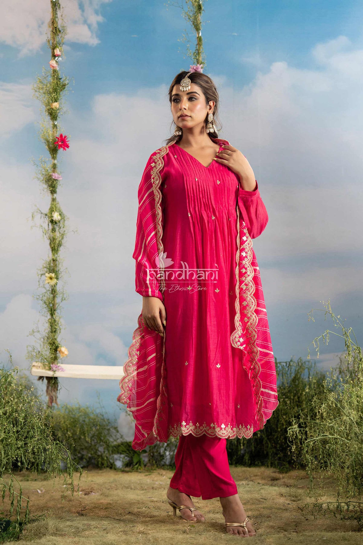 Woman in a bright pink traditional outfit with floral decorations against a natural background