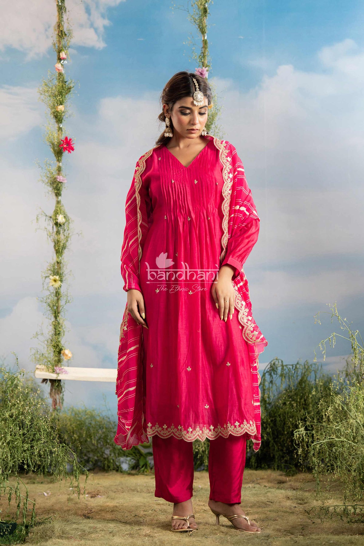 Woman in a pink traditional outfit with floral decorations against a natural background