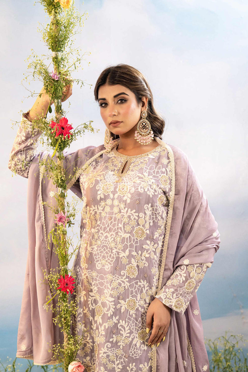 Woman in traditional attire holding flowers against a light background