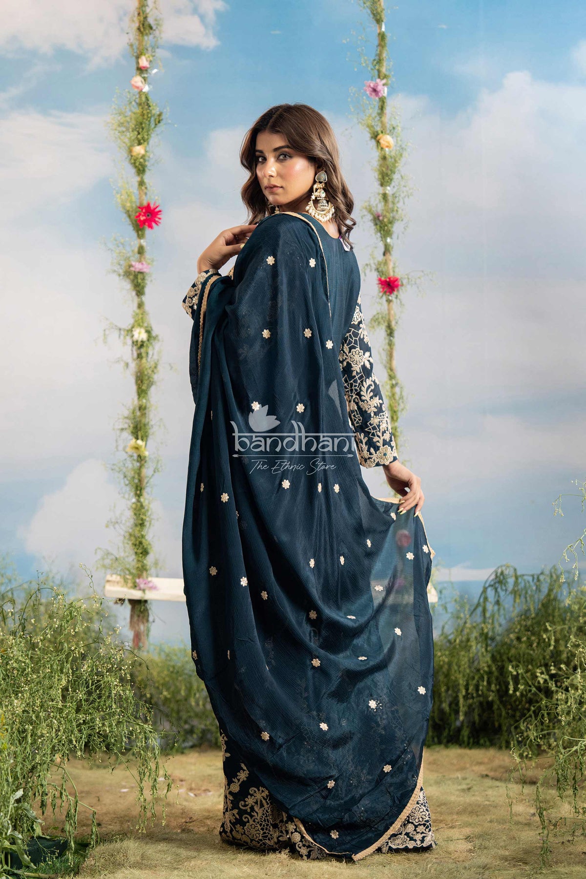 Woman in a blue saree with floral decorations in the background