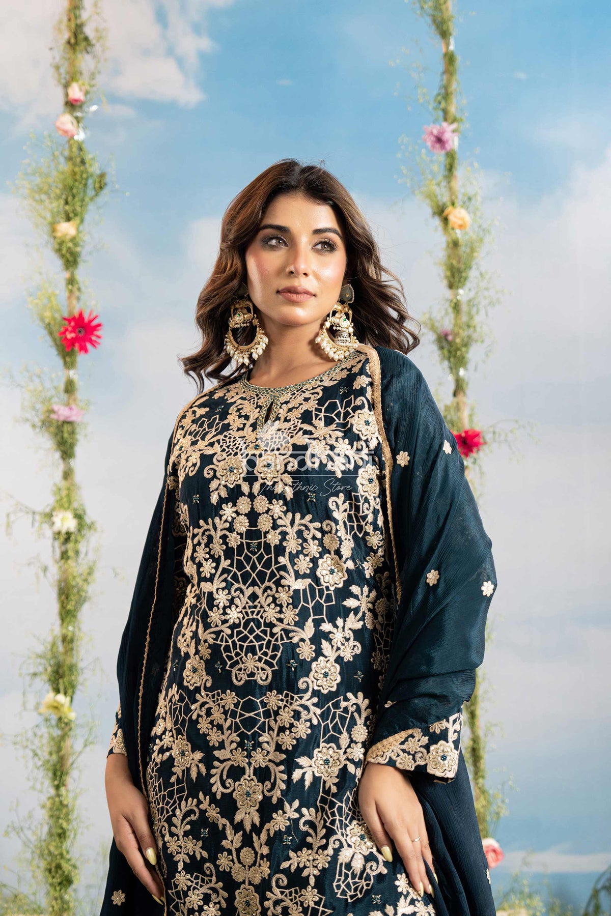Woman in traditional embroidered outfit with floral decorations in the background