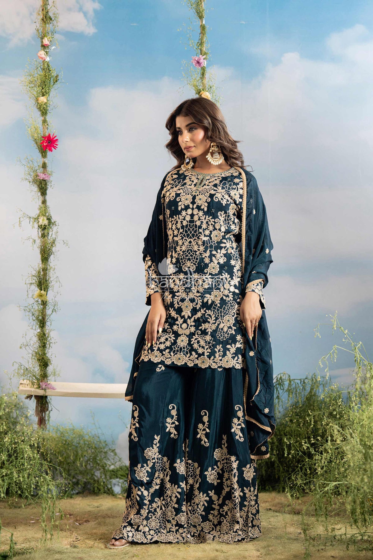 Woman wearing a dark blue embroidered outfit with floral decorations against a sky background.