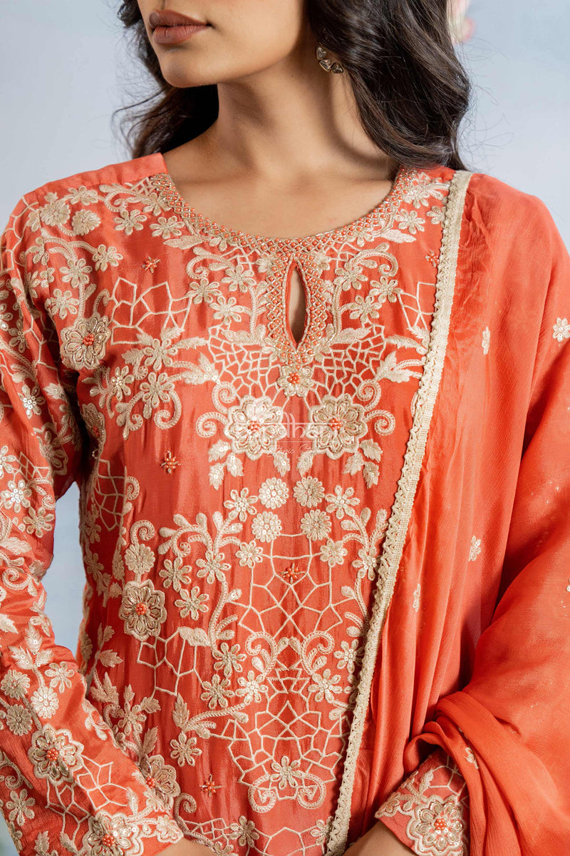 Coral pink traditional outfit with intricate white embroidery on a light gray background