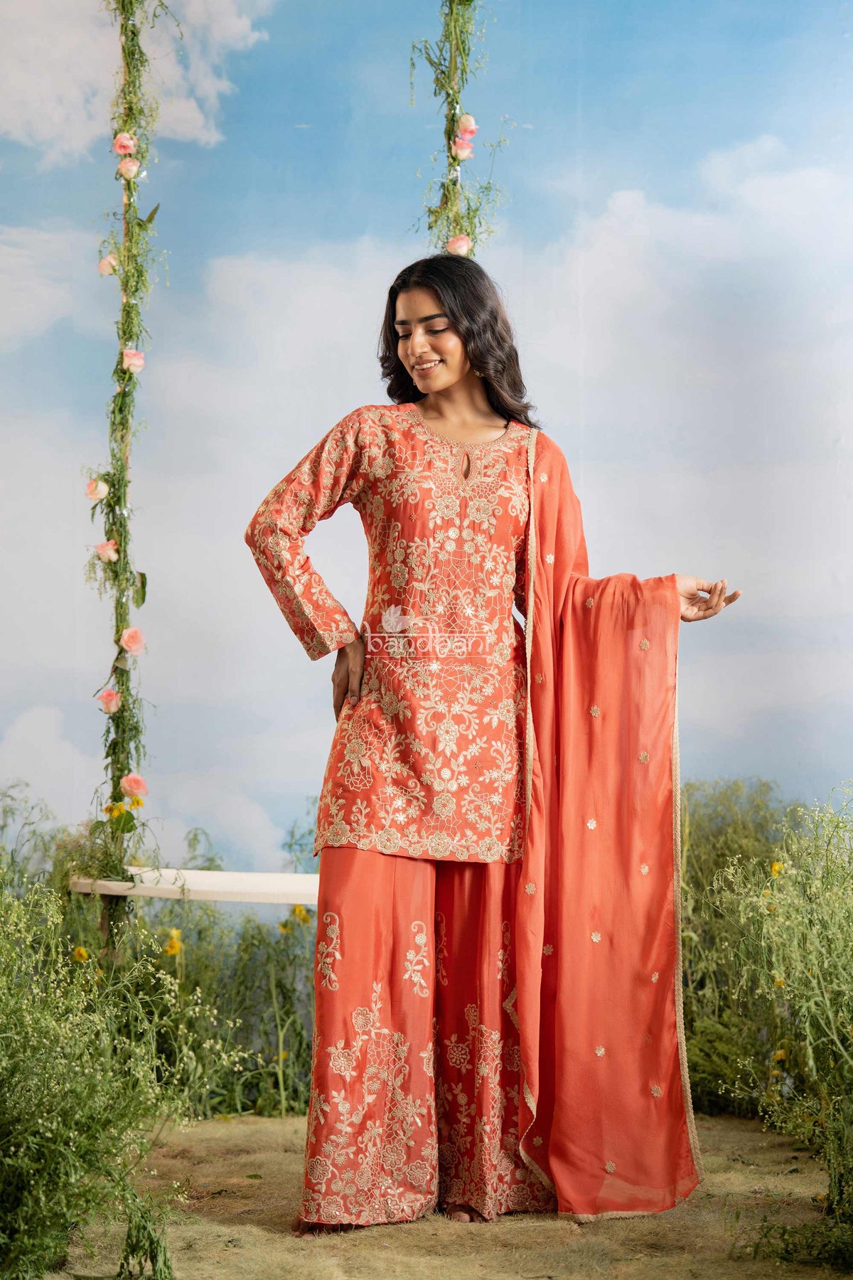 Woman in a floral dress standing outdoors with a swing and greenery in the background